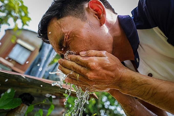 Rửa mặt bằng nước lạnh là cách mà người dân thường áp dụng để chống nóng. (Ảnh: VnExpress)